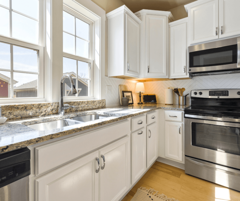 A bright, modern kitchen with white cabinets, granite countertops, and a clean stainless steel stove. This sparkling clean kitchen serves as a visual example of the results you can achieve with a professional cleaning shortcut.